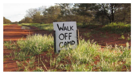 A sign on a dirt path that reads "Walk Off Camp"