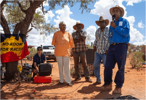 Banjo and other senior men  perform ceremonial song at the opening of Protest House.