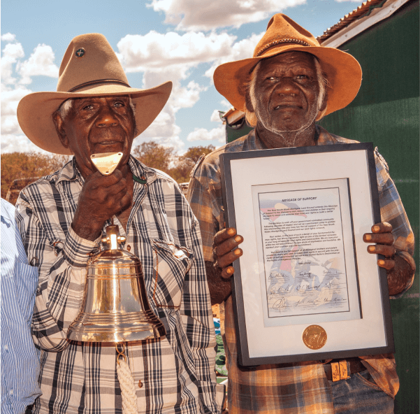 a photo of Frank Holmes holding the brass Declaration Bell and Banjo Morton holding the Declaration Bell certificate