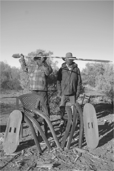 A black and white photo of two Alyawarran men standing holding a piece of equipment 